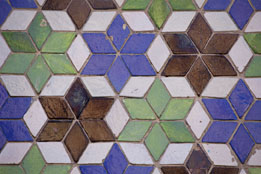 This is a photo of Moorish tiles Alhambra with a repeating star shape in green, blue, and rust.
