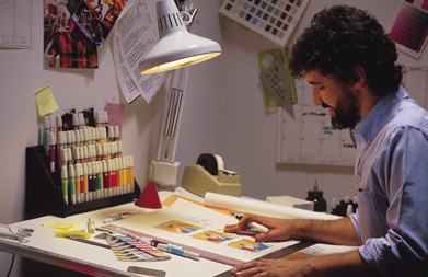 This photograph shows an artist at work at a drawing table.