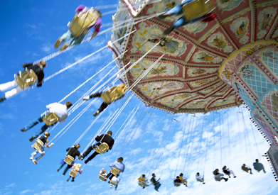This photo  shows a view from below of people on an amusement park ride.