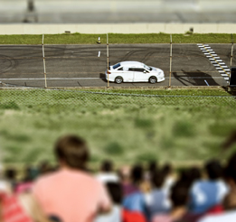 This photo shows a race car being driven past a crowd of spectators.