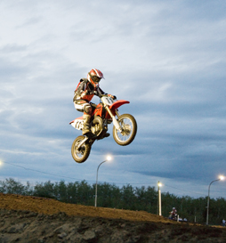 This photo shows a motorcycle rider jumping in the evening. 