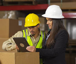 In this photo, workers are using a digital tablet in a shipping warehouse.