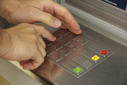 This is a photo of a bank PIN pad and a person entering a code.