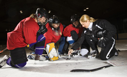 This photo shows a coach talking with a hockey team.