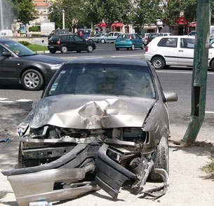 A photograph shows a grey sedan with a crumpled hood and front end as a result of a collision.