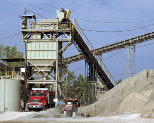 A photo shows a dump truck getting filled with a load of sand.