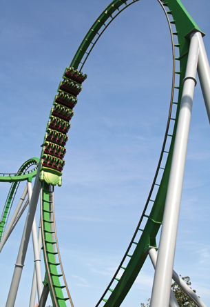 The photograph shows a green roller coaster ride with a large, looping track.