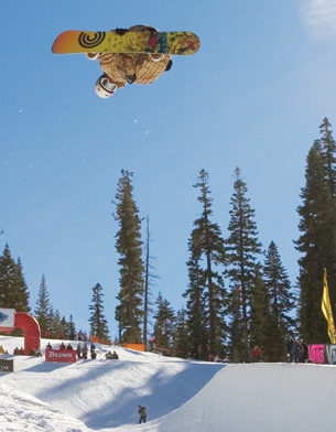 A photograph shows a snowboarder in the air performing an aerial maneuver. 