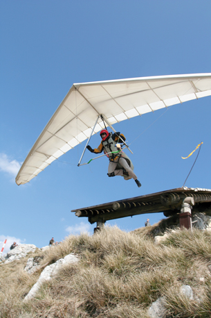 A photograph of a man using a hang-glider and leaping off a platform is shown.