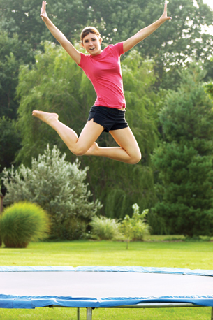A photograph shows a girl in mid-air after jumping on a trampoline.