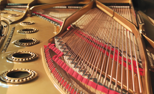 A photograph shows the inside of a grand piano. There are strings attached to each key of the keyboard.