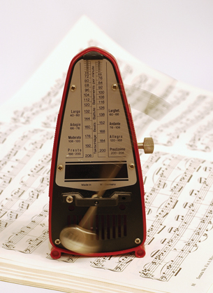 A photograph shows a metronome placed on a book of sheet music.