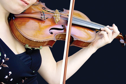 A female musician plays the violin in this photograph.