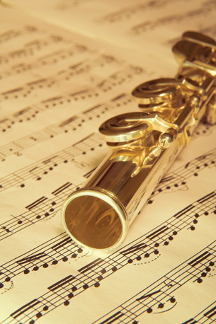 A photograph shows a flute resting on a piece of sheet music.
