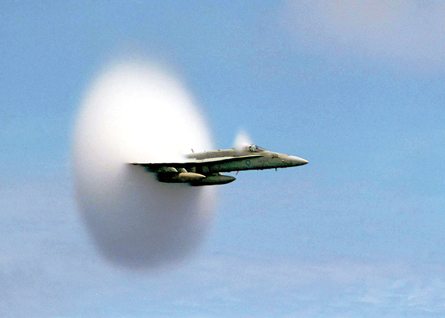 A photograph shows a jet plane coming out of a cloud that it has created by flying at the speed of sound.